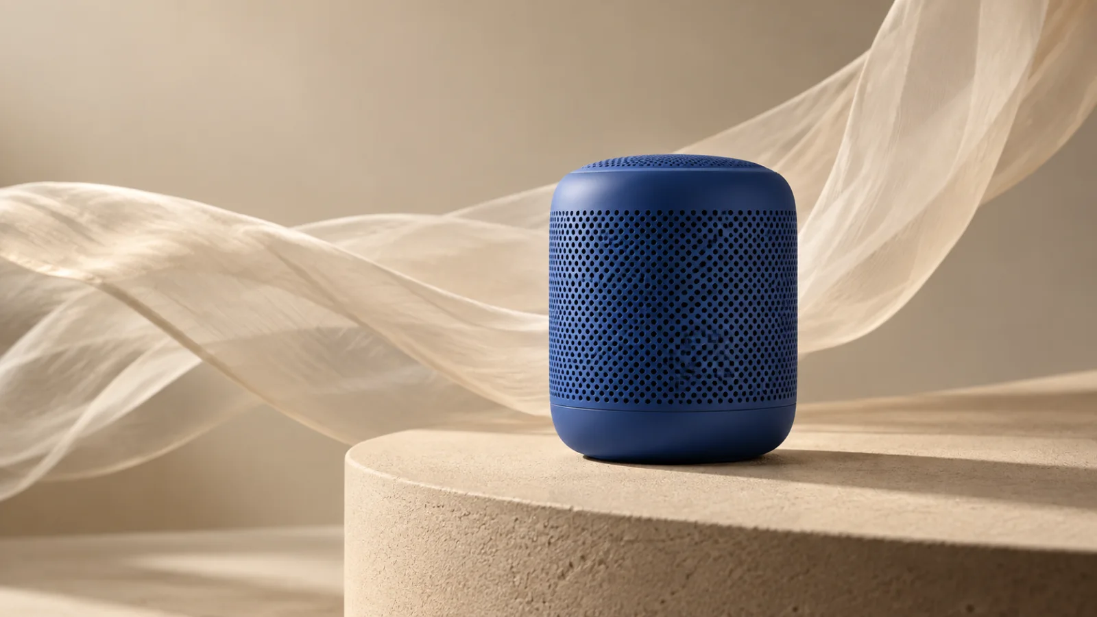 Unbranded cobalt speaker on a stone plinth with flowing fabric